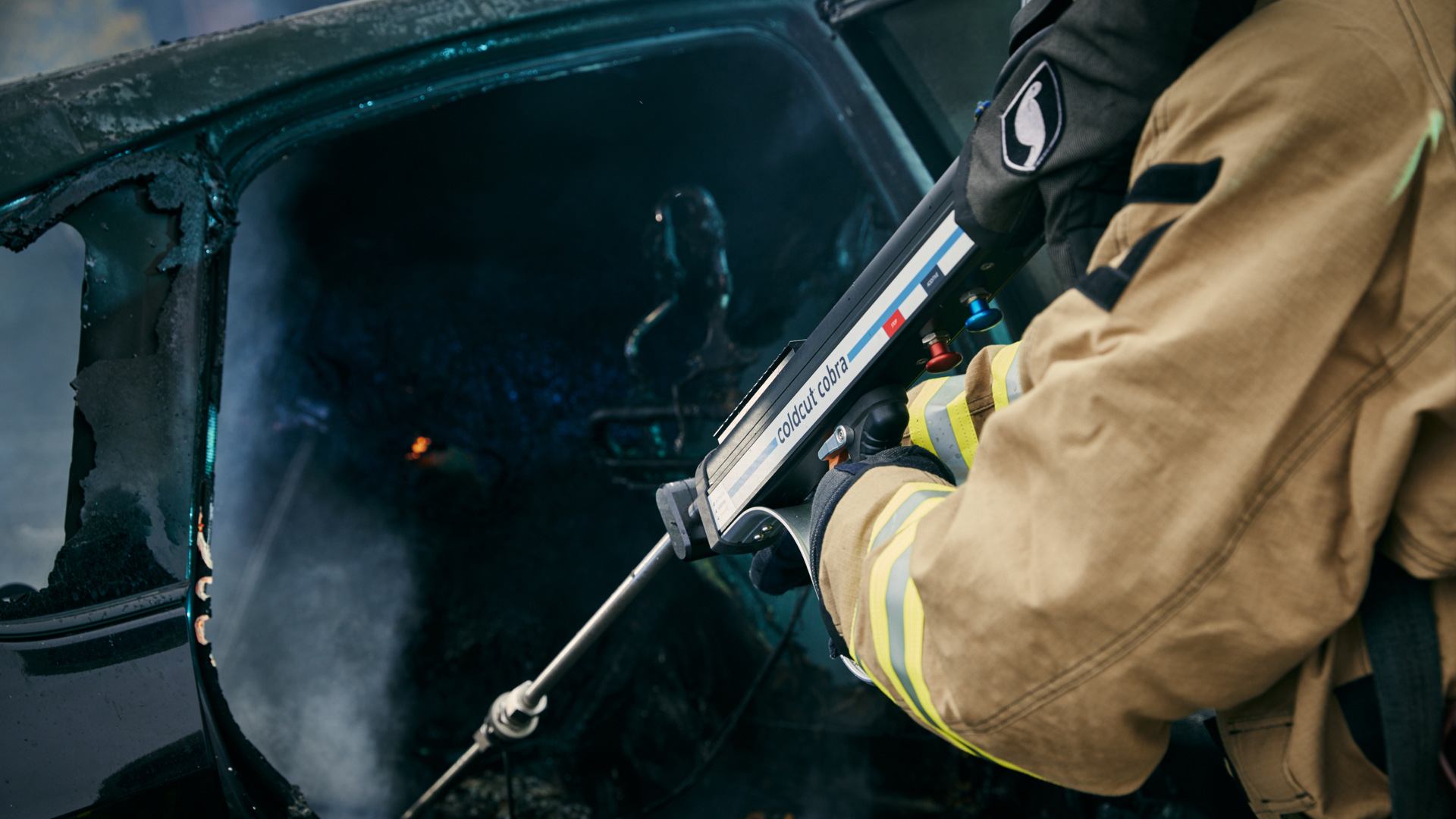 A firefighter is putting out an EV car fire using the Cobra tool.